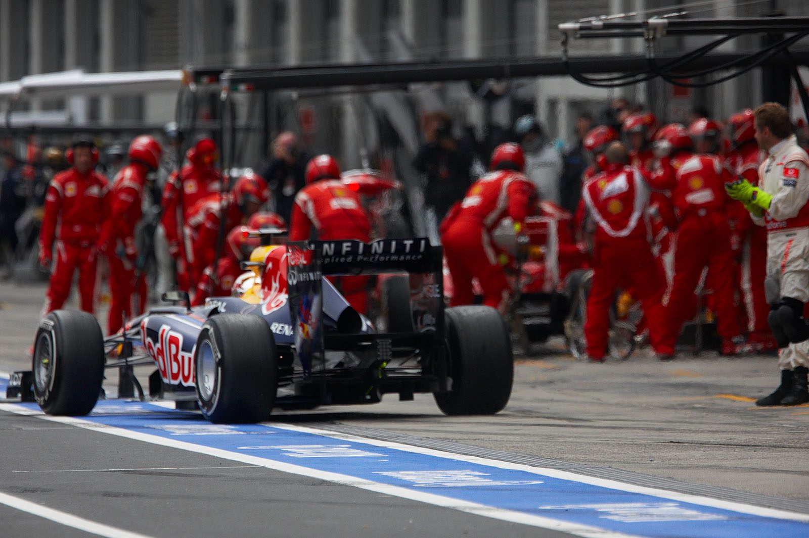A McLaren mechanic encourages Vettel who overtakes the slower pitting Massa
