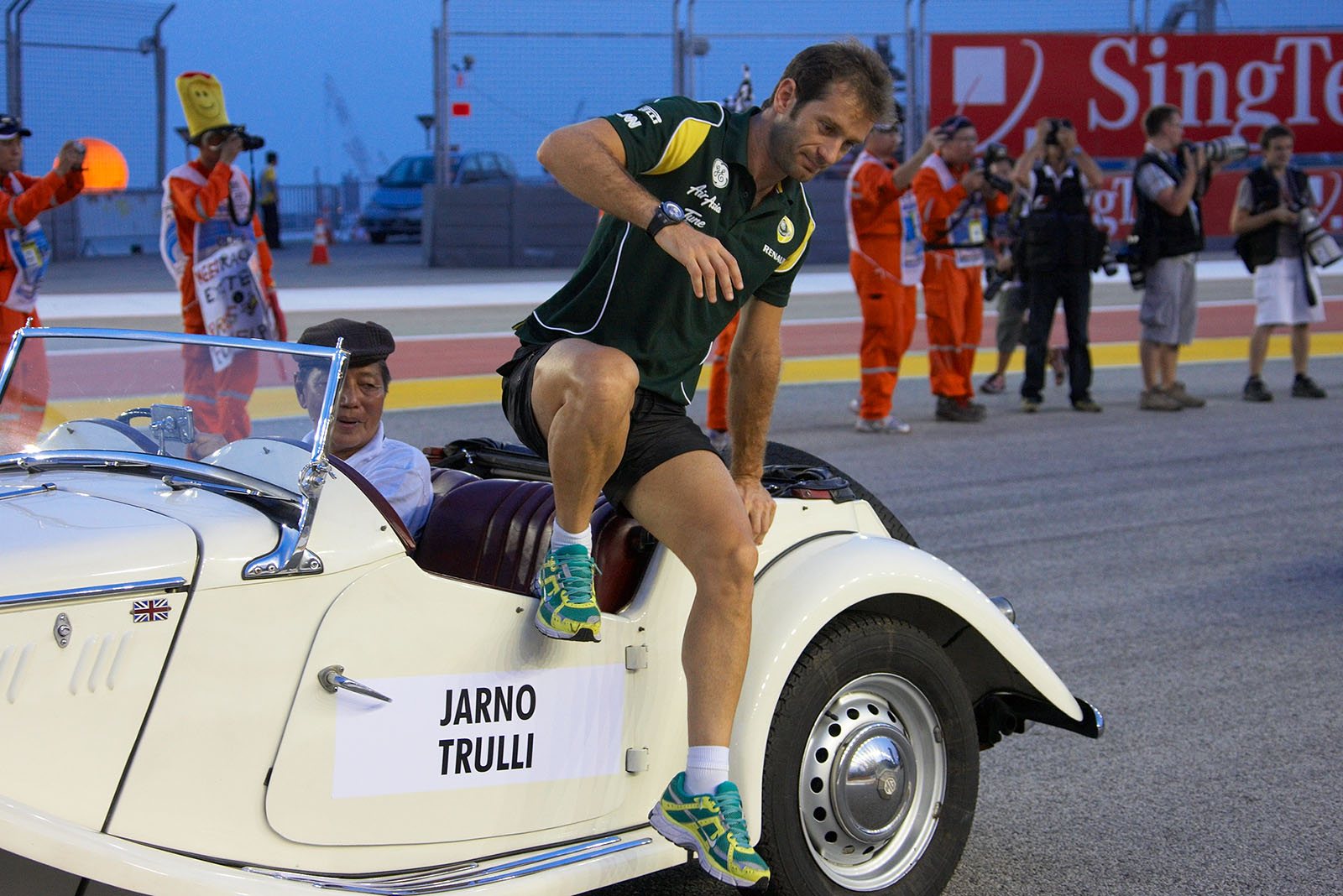 A motivated Jarno Trulli jumps from the drivers parade vehicle
