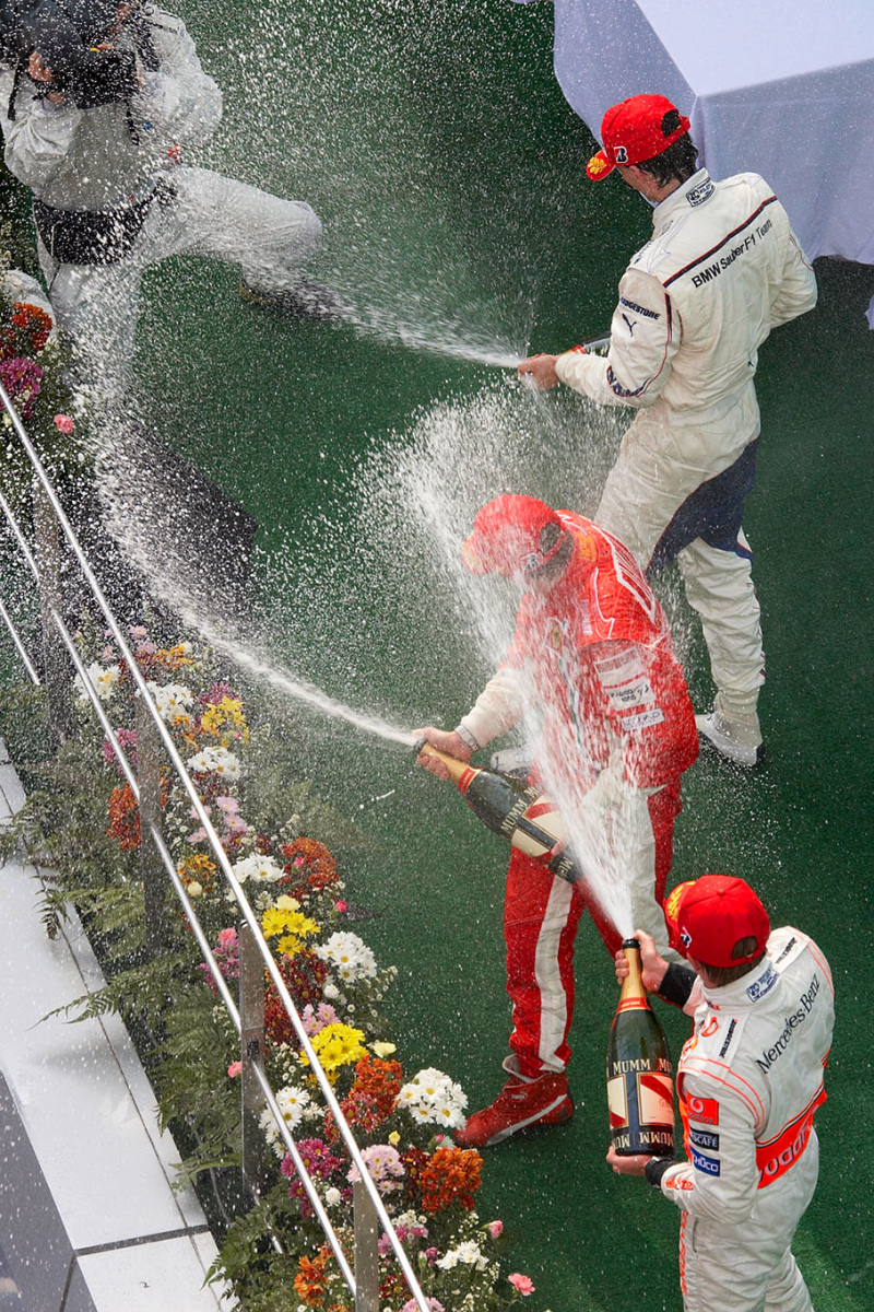 A FOM TV camera man is being showered by three spurts of champagne