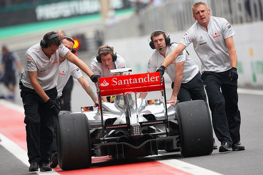 Lewis Hamilton is being pushed back to pits by the McLaren mechanics after the practice session was stopped because of aquaplaning
