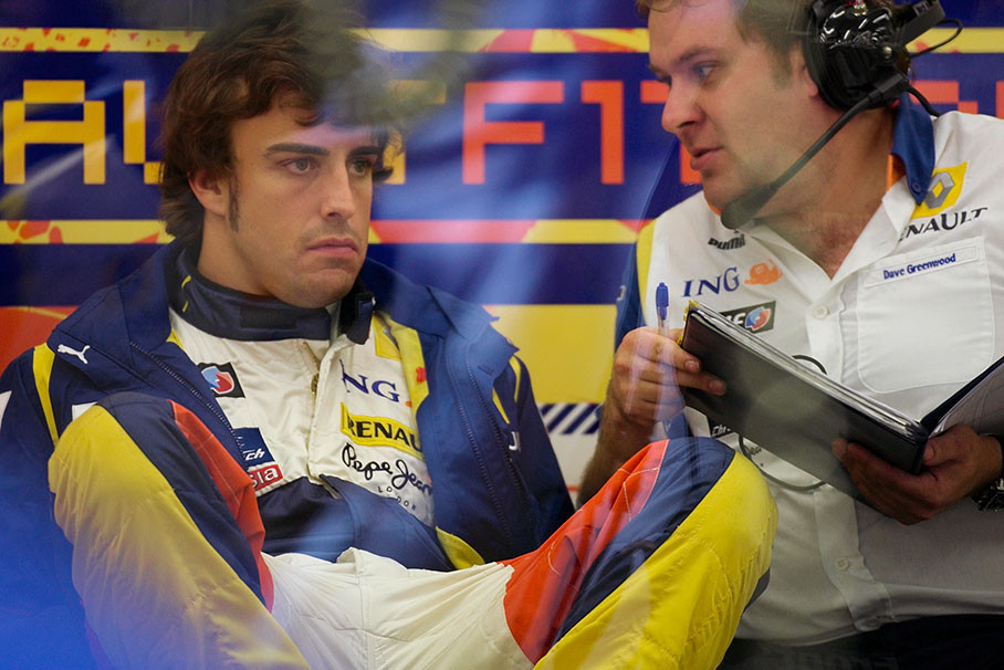 Fernando Alonso sits in a glass cabinet at the rear of Renault pits