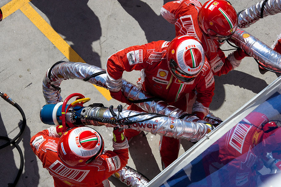 Ferrari mechanics check the fuel hoses and nozzles