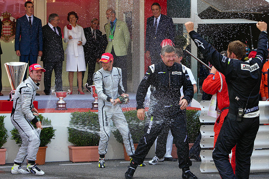 Second placed Rubens Barrichello and winner Jenson Button celebrate their spectacular double win with champagne showers on team boss Ross Brawn in front of Monaco's podium