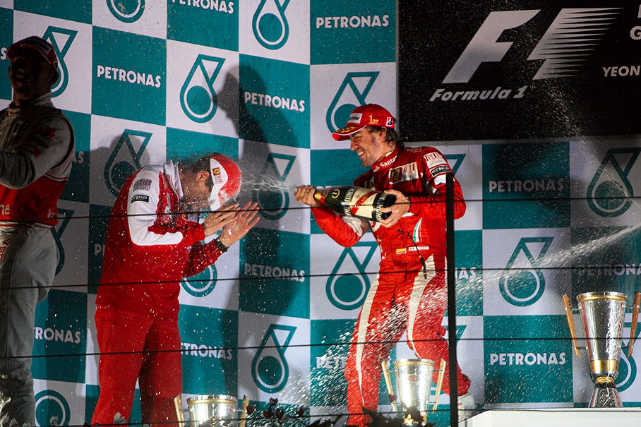 Race winner Alonso sprays champagne showers over Ferrari engineer Chis Dyer after the podium ceremony