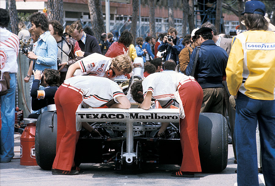Ferrari mechanics study the engine of Lauda's victorious Ferrari 312T on the grid's pole position before the Monaco GP 1975