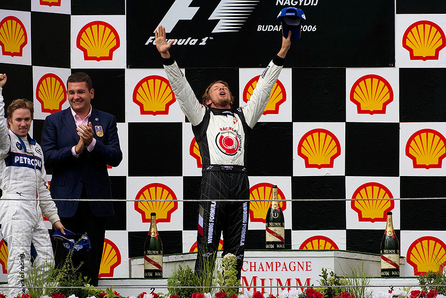 Jenson Button celebrates on Hungary's podium in the few sun rays which are illuminating his first victory