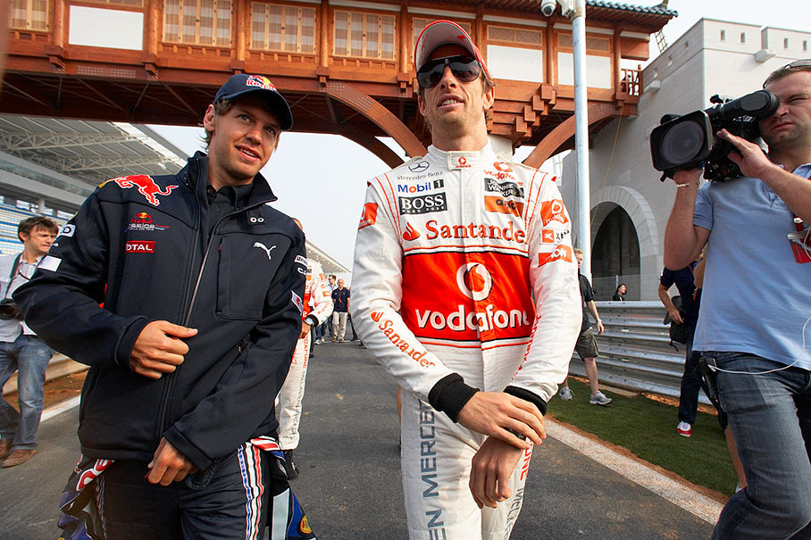 Sebastian Vettel and Jenson Button walk together to a group photo shooting