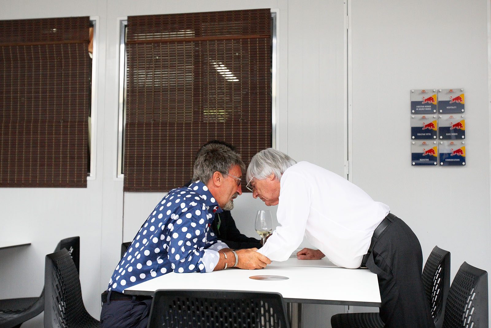 It is loud in the paddock, and Eddie Jordan seems to tell a secret to Bernie Ecclestone