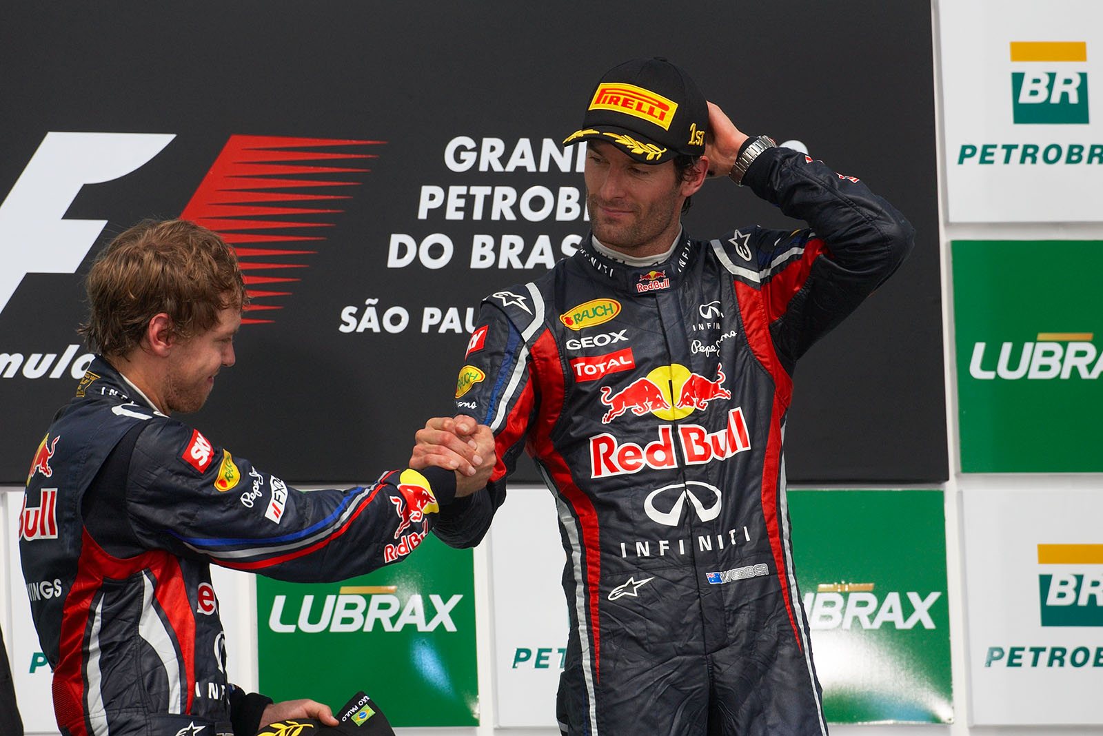 Red Bull's race winner Mark Webber and second placed team mate Sebastian Vettel ashake hands on the podium after the Brazilian Grand Prix