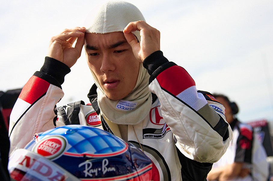 Concentrated Takuma Sato putting his balaclava on.