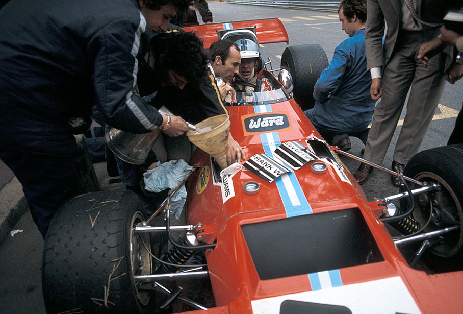 Whilst the De Tomaso-Cosworth 505 is being refueled, Piers Courage speaks with team boss Frank Williams