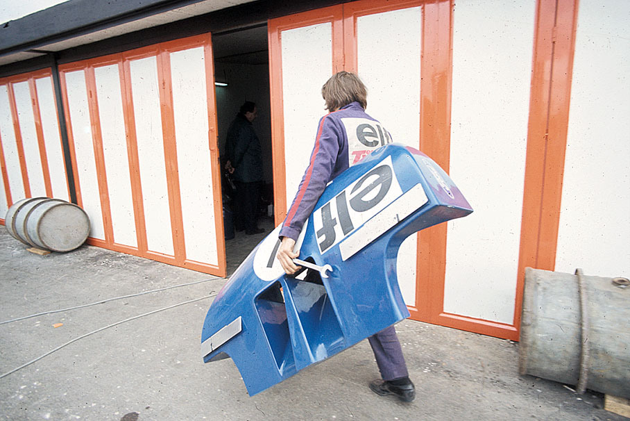 A Tyrrell mechanic carries a front wing cover