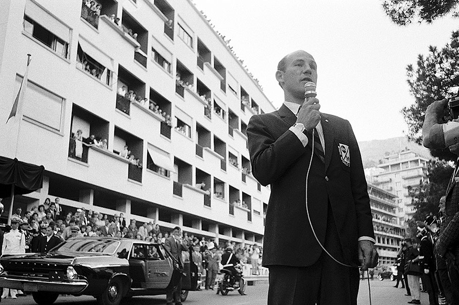 Stirling Moss reports from the grid in front of the limousine of Prince Rainier and Princess Grace, GP Monaco 1964