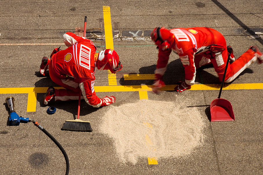 Ferrari mechanics sweep some remains away after Massa's flamy pitstop