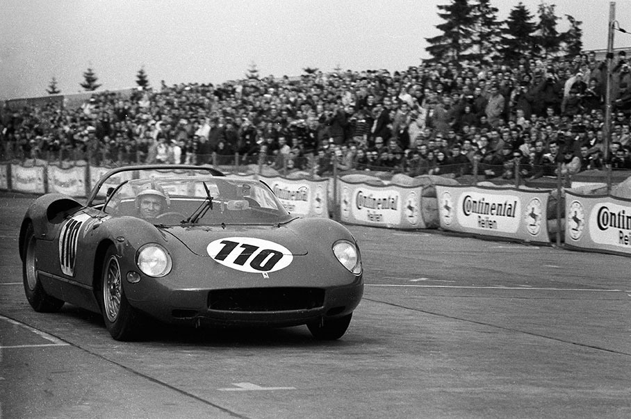 A smiling and waving Willy Mairesse (B) passes the finish line in the winning Ferrari 250 P #0812
