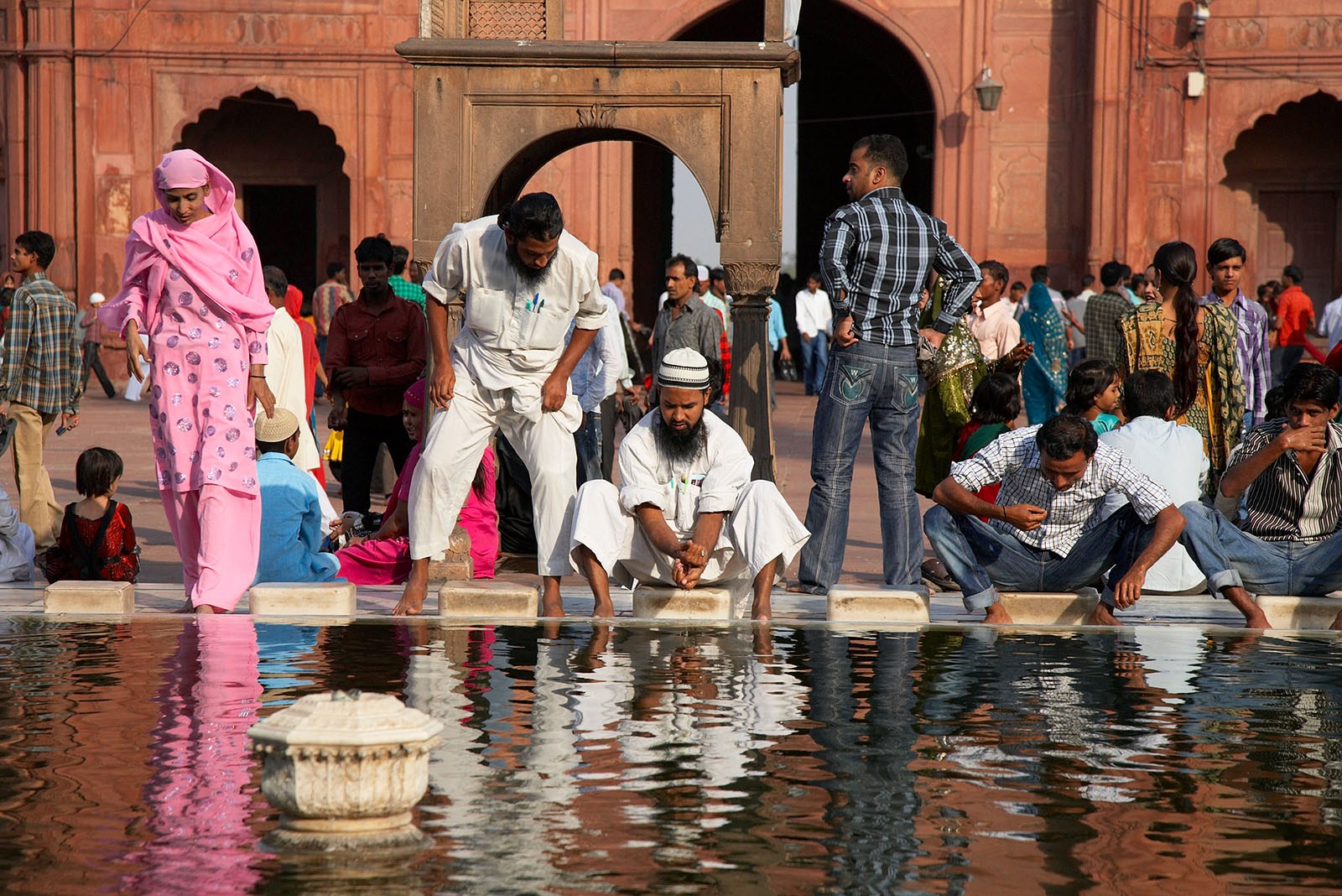 Muslim believers wash their faces and feet in the fountain before they attend the prayers in the Jama Masjid temple