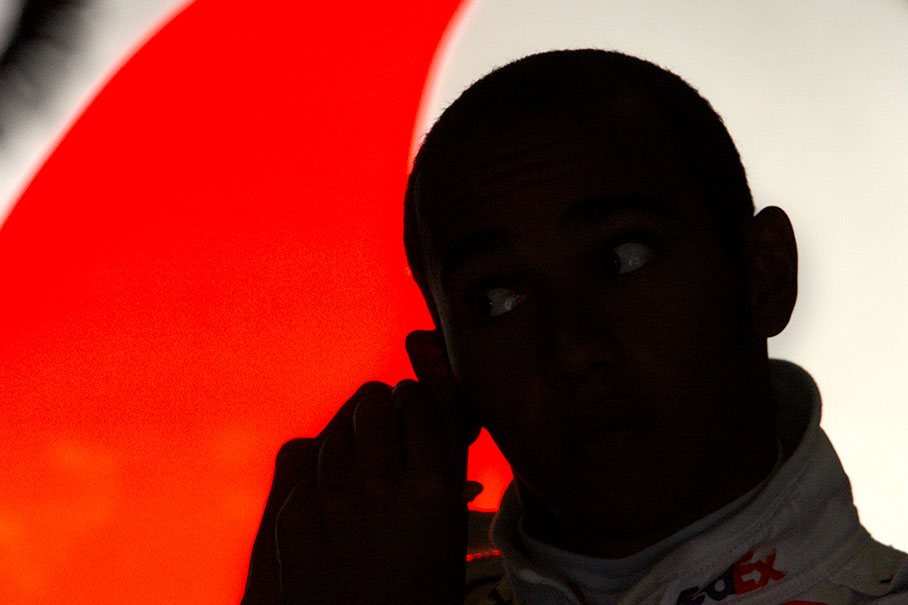 Lewis Hamilton inserts the ear plugs in a dark McLaren Mercedes pits