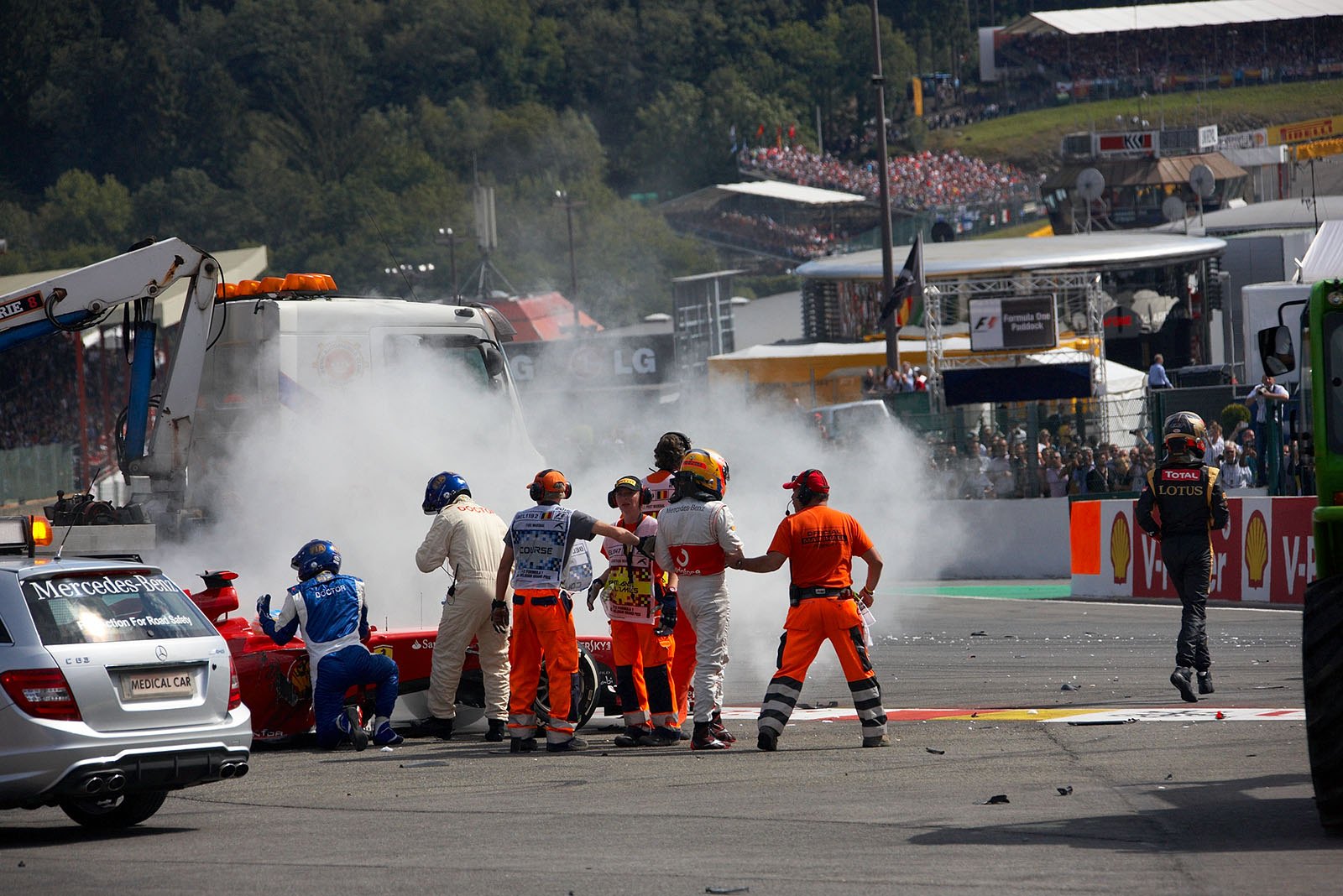 Several marshals and FIA race doctor Gary Hartstein take care of Fernando Alonso in his destroyed Ferrari race car after the start accident