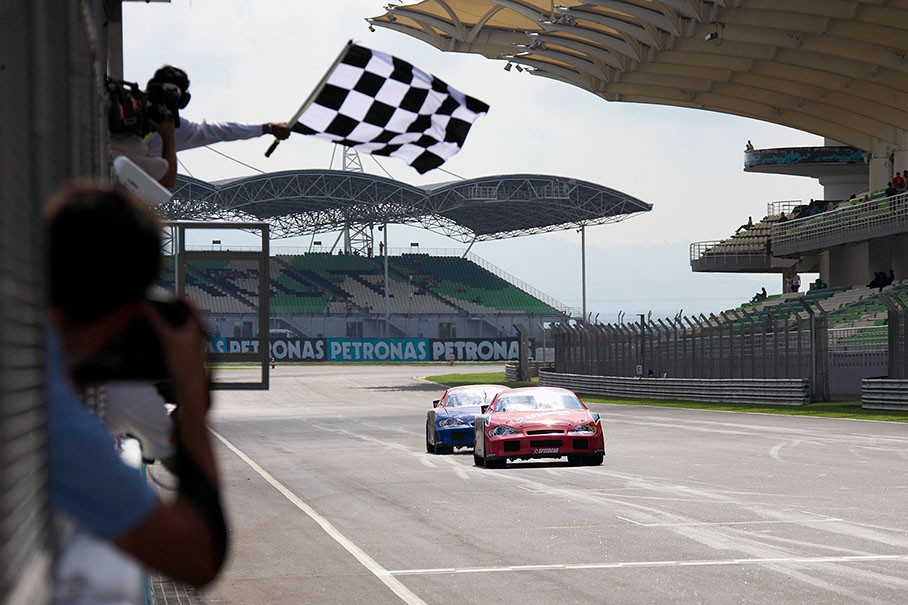 Jean Alesi takes the chequered flag in the Speedcar race