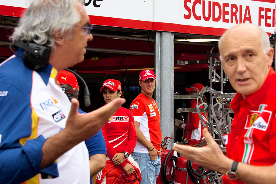Michael Schumacher and Felipe Massa in front of pits watch discussion of gesticulating Renault boss Flavio Briatore and Ferrari's head of PR Antonio Ghini