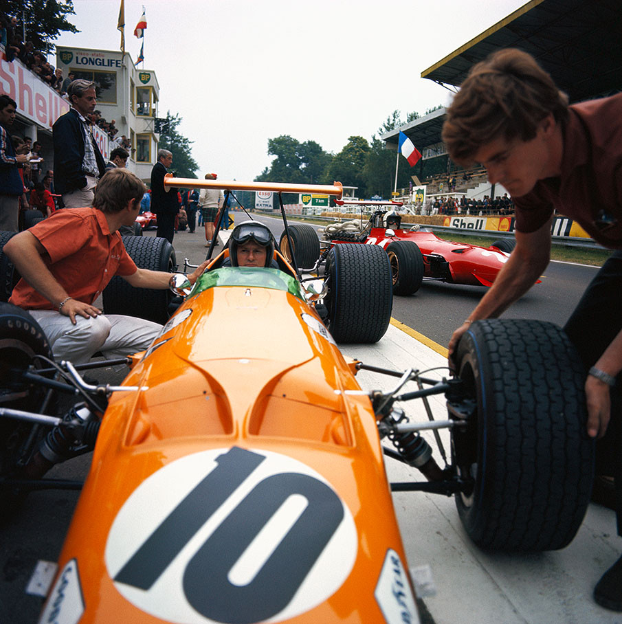 Bruce McLaren getting new tyres while Chris Amon's Ferrari is about to leave the pits.