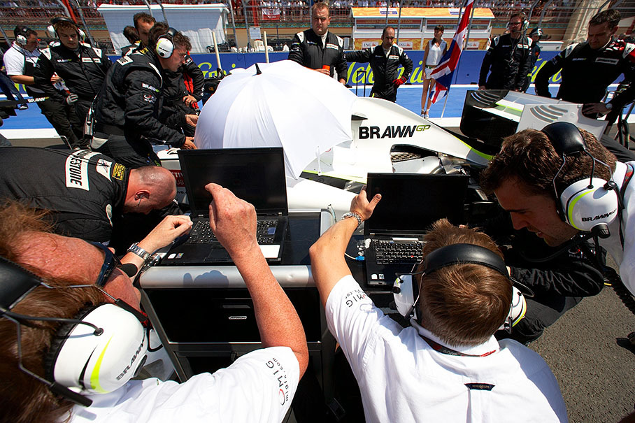 Brawn GP mechanics and engineers shimmer around Jenson's car
