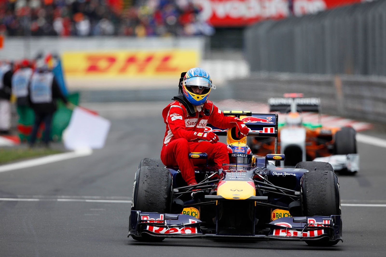 Second placed Fernando Alonso of Ferrari has parked the car besides the track as engine saving precaution and gets a lift from Red Bull's third placed Mark Webber