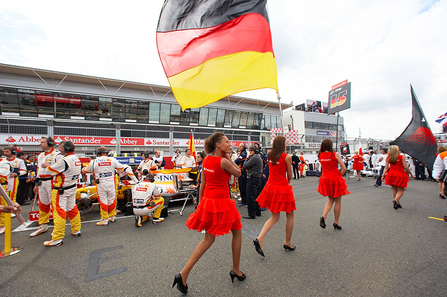 Grid girls with flags march to the grid positions
