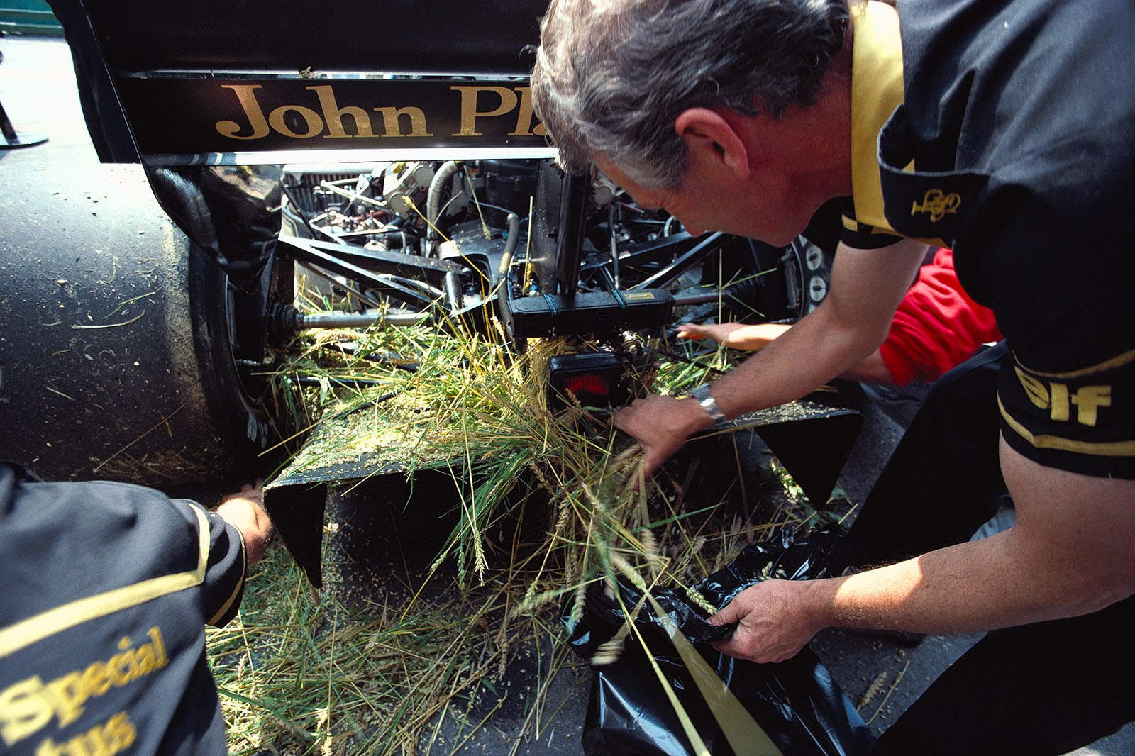 JPS-Lotus car back in pits for cleansing after it whent off the track and plowed a wheat field