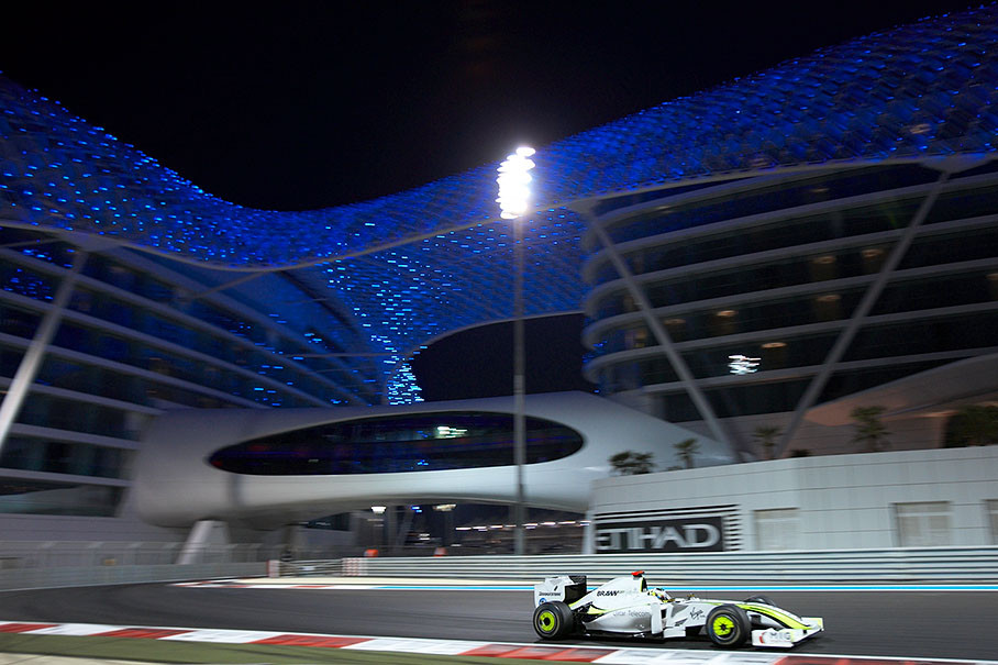 Jenson Button, Brawn Grand Prix, passes the illuminated Yas Marina Hotel complex