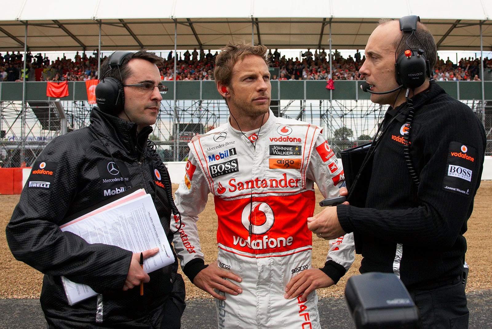 Jenson Button amidst McLaren engineers on the grid