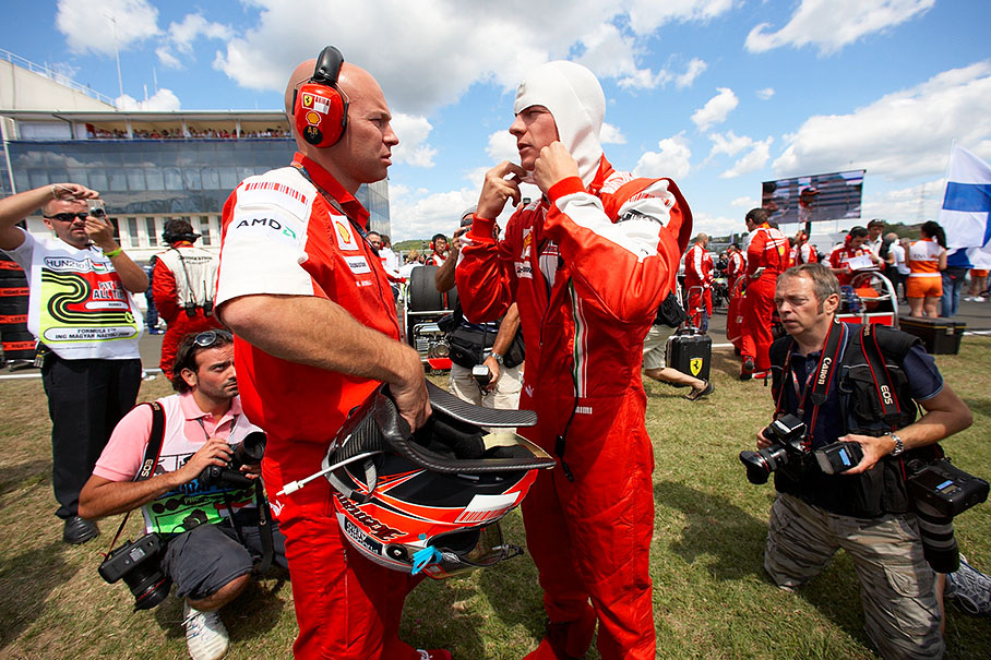Precautious photographers approach Ferrari's Raikkonen carefully on their knees