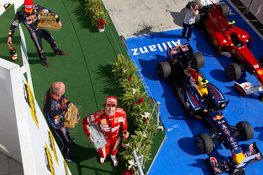 Second placed Alonso leaves the podium with his trophy and a bottle of champagne