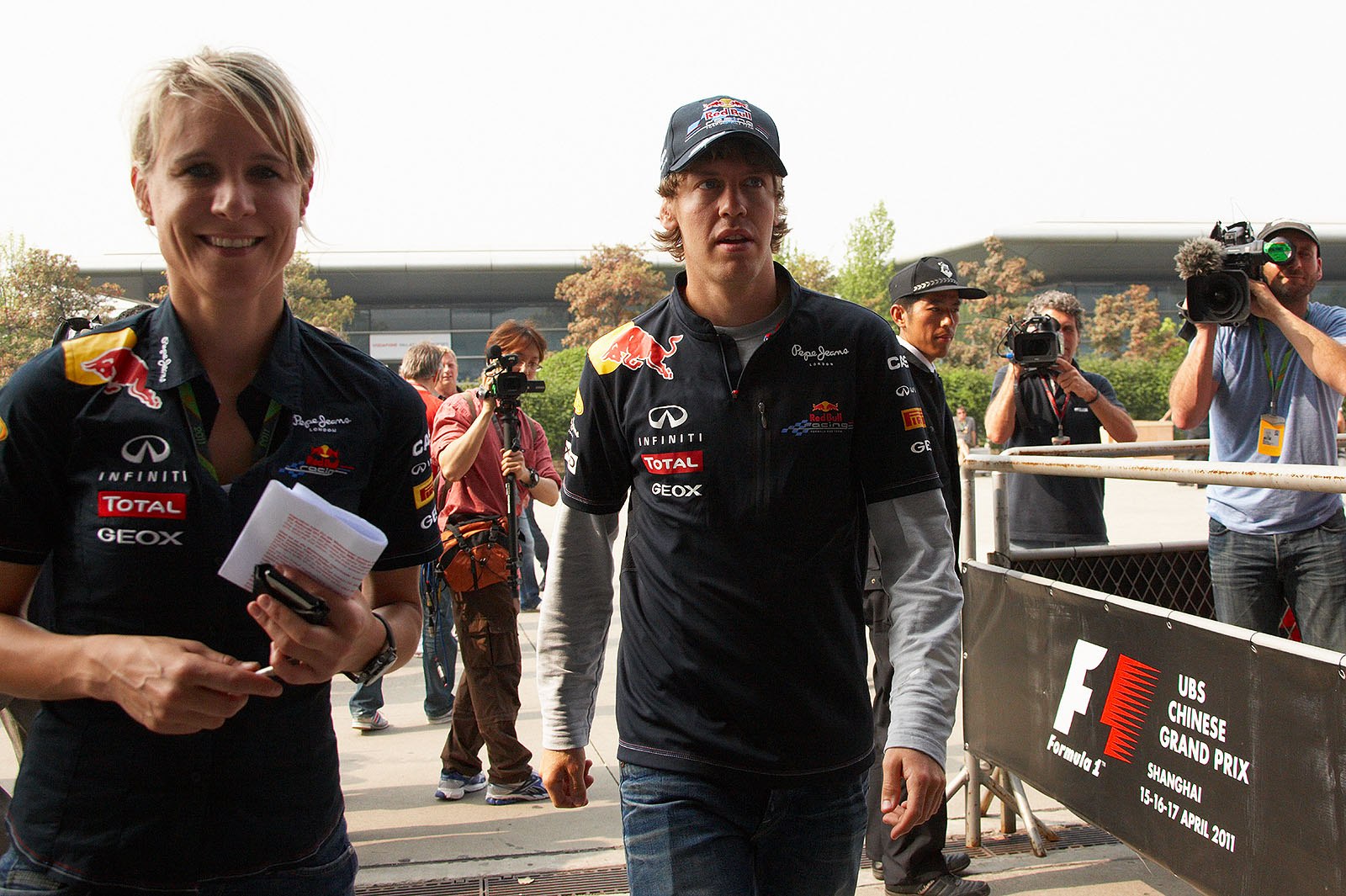Red Bull press officer Britta Roeske leads World Champion Sebastian Vettel to the press conference