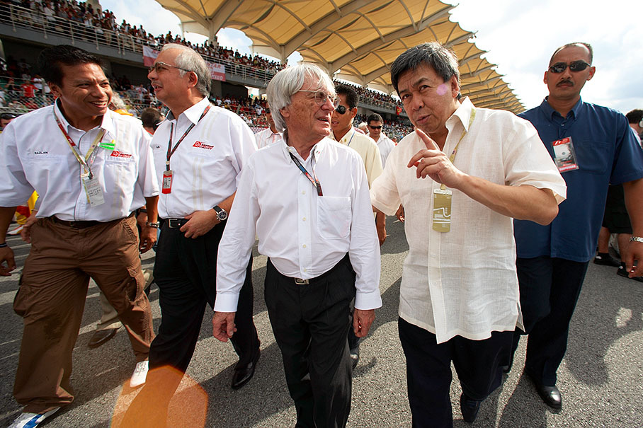 Formula One promotor Bernie Ecclestone takes his VIP guests, Malaysian politicians, around for a walk on the grid