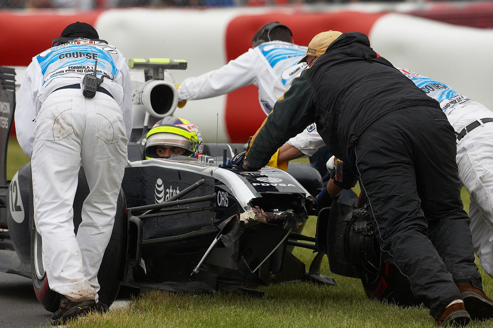 Pastor Maldonado's damaged Williams car is pushed away after crashing into the wall