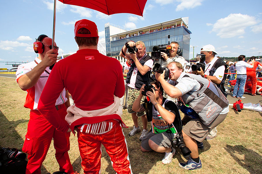 Photographers take portrait photos of Raikkonen besides grid