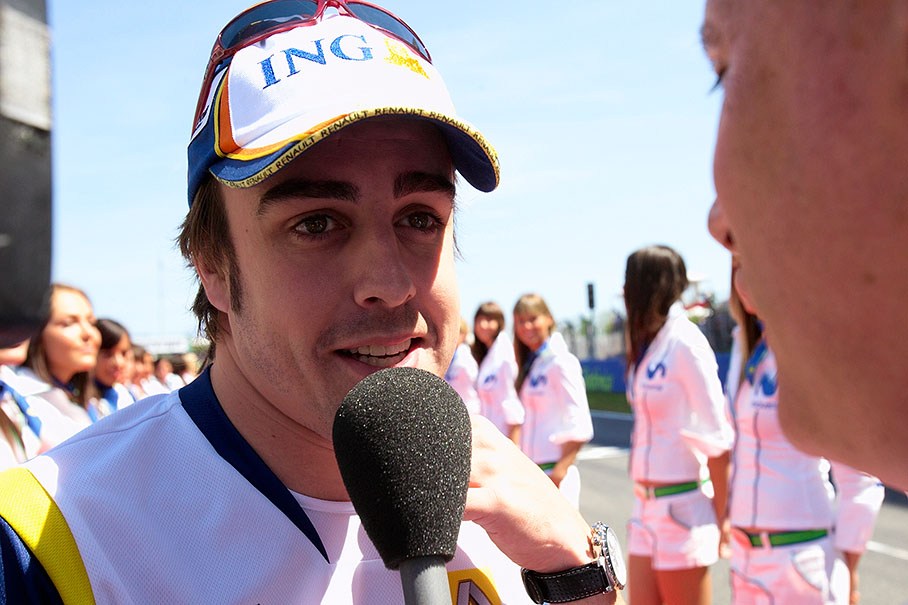 Local hero Fernando Alonso is being interviewed between the grid girls