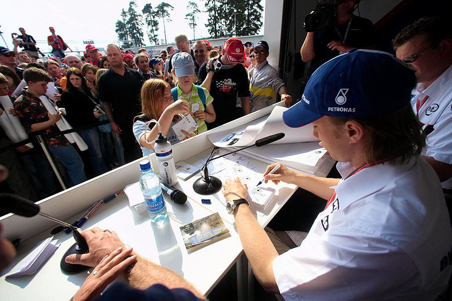 Nick Heidfeld signing memorabilia and posters of visitors of the experience park during the "autograph hour"