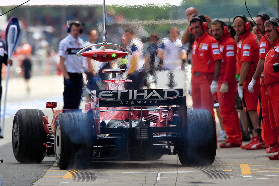 Kimi's Ferrari mechanics watch their driver placing a rubber mark at the pit