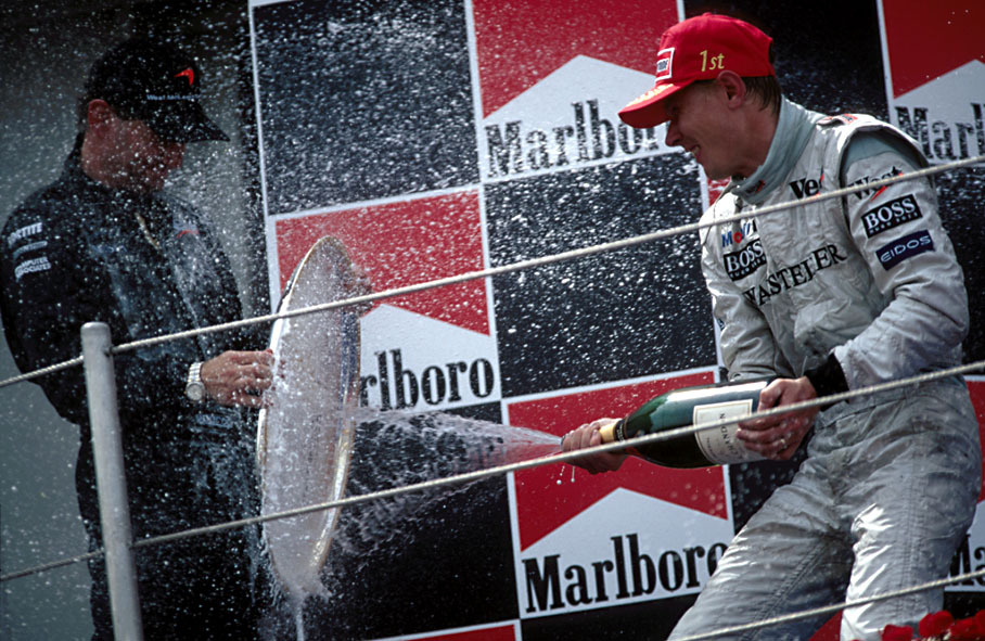 Mika Häkkinen sprays champagne at Adrian Newey