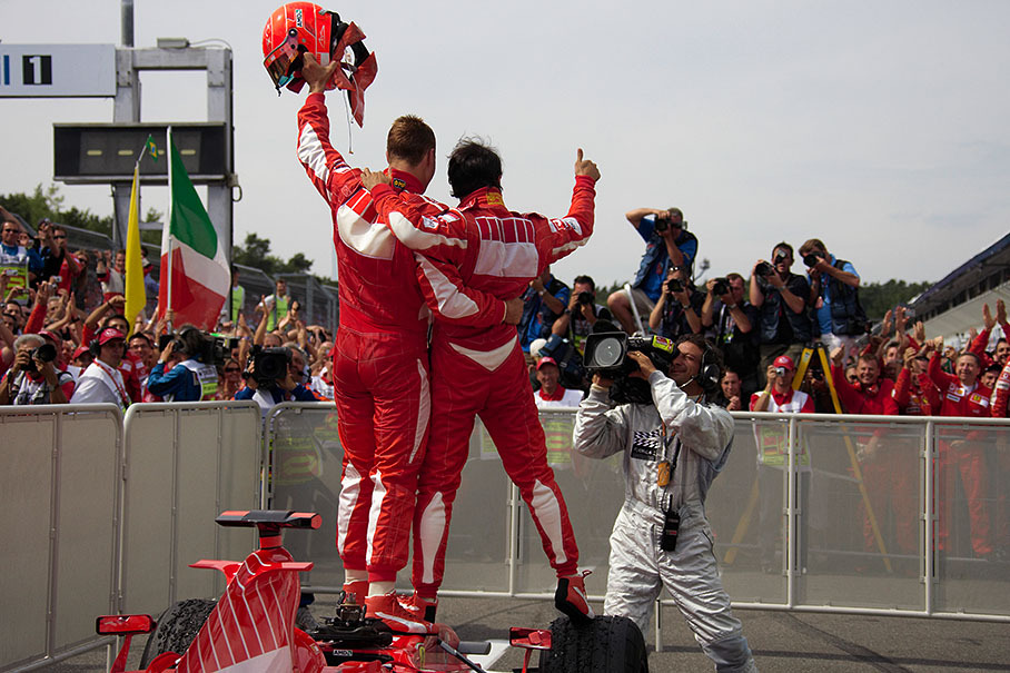Michael Schumacher and Felipe Massa posing for the media and their team