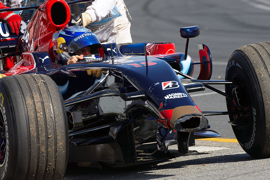 A disappointed Sebastian Vettel is being pushed out of danger with a broken nose