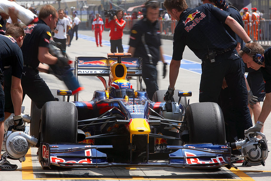 Mark Webber practises pitstops with the Red Bull Racing crew