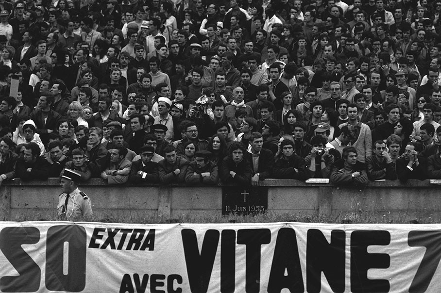 Fans on the grandstand behind the memorial stone for the fatal race accident of a Mercedes-Benz 300 SLR driven by Pierre Levegh which killed 86 people in 1955