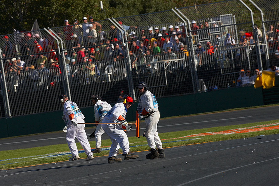 Busy marshals try to clean the track from dangerous carbon fiber debris