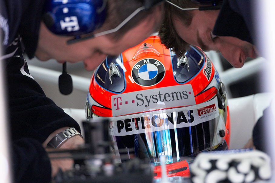 Robert Kubica is being strapped into his BMW Sauber car's cockpit