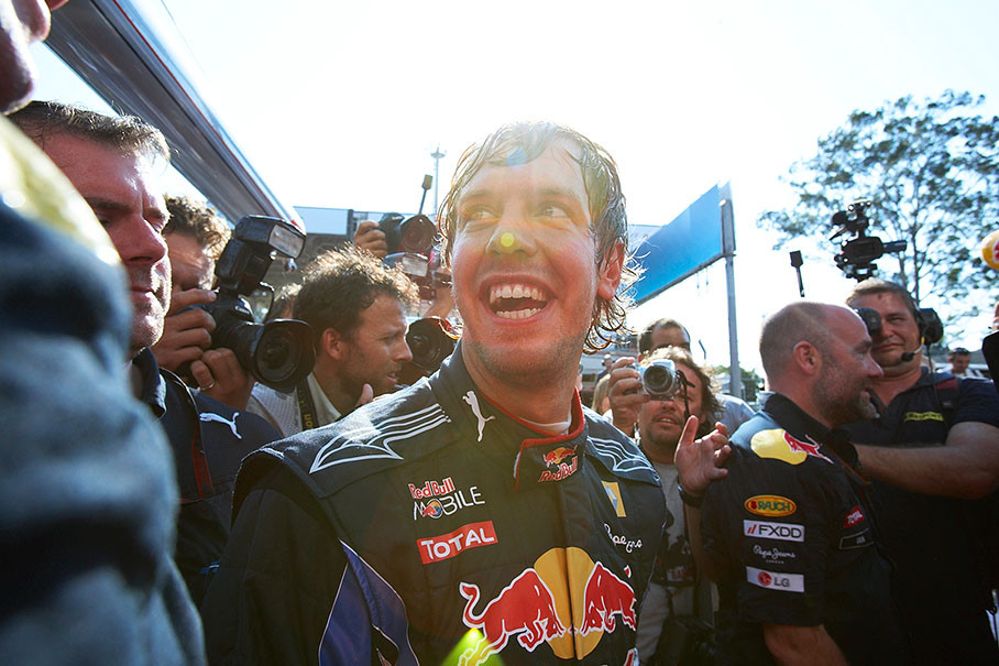 Media and Red Bull team members buzz around Sebastian Vettel after the race