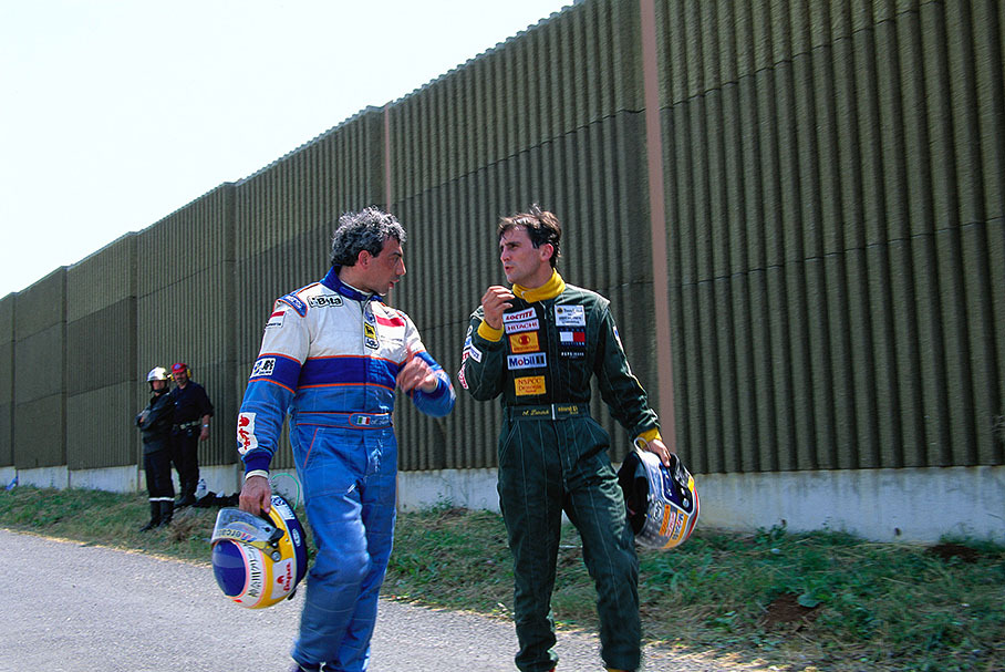 Alex Zanardi (Lotus) in friendly discussion with Michele Alboreto (left, Minardi), both walking back to pits after retiring with engine failures