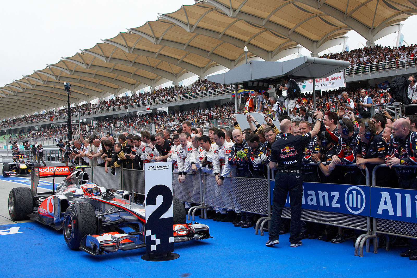 While Adrian Newey celebrates the Red Bull victory with his mechanics, second placed Jenson Button on McLaren Mercedes already parks in parc ferme. The outstanding winner Vettel arrives from the backside.